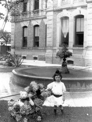 Girl strolling Teddy bear on the Courthouse lawn, Columbus Texas vintage photo 